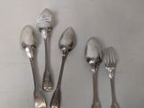 three spoons and two forks are sitting next to each other