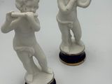 deux figurines représentant un garçon jouant de la trompette et une fille jouant de la flûte