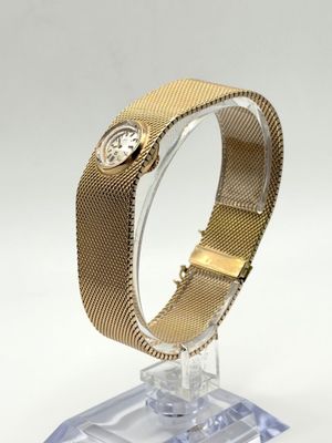Gros plan sur une montre-bracelet posée sur un support, sur une surface blanche