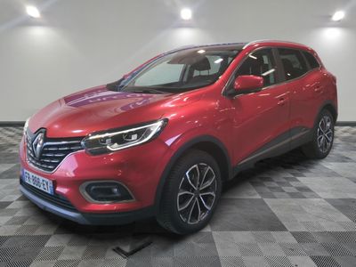Une voiture rouge est garée sur un sol à damier dans un showroom.