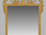 an ornately carved mirror with a gold frame on a gray background