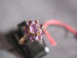 a ring with a pink flower on it sitting on a cell phone