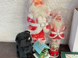 a small black cat sitting next to a santa claus figurine on a table