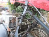 a close up of a tractor with a red trailer in the background
