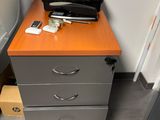 a filing cabinet with a printer on top of it next to a desk