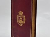 an old red book with a gold emblem on the cover