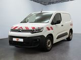 une camionnette Citroën rayée de rouge et de blanc, garée dans une pièce blanche