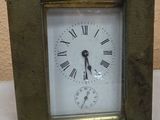 a small metal clock with roman numerals on the face
