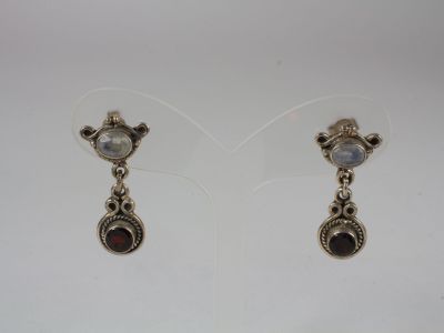 a pair of silver earrings with garnets on them