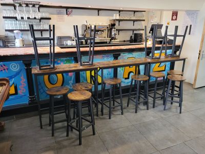 Plusieurs tabourets sont alignés devant un bar dont les murs sont couverts de graffitis