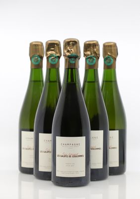quatre bouteilles de vin sont alignées sur une surface blanche