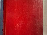 un vieux livre rouge posé sur une table blanche