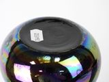 a colorful glass vase with a black lid on a white table