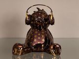 un ours en peluche marron avec des écouteurs, assis sur une table en verre