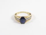 gros plan d'une bague en or avec une pierre bleue et des diamants