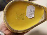 someone is holding a yellow shoe with a tag on it