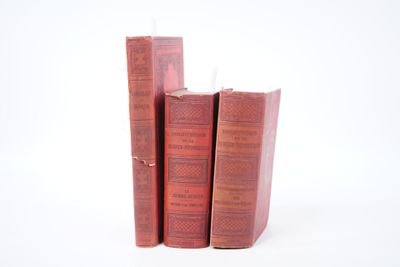 trois livres rouges empilés les uns sur les autres sur une surface blanche