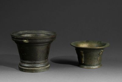 pair of bronze vases on a gray surface with a gray background