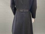 the back view of a mannequin wearing a black coat and white pants