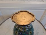 a blue vase sitting on a table with a gold lid