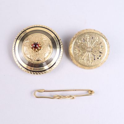 a gold broocht and a pin on a white surface