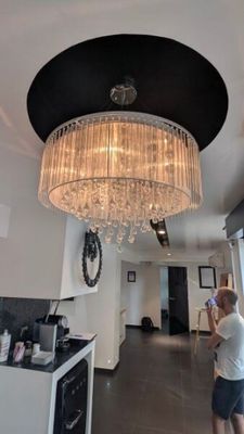 un homme debout dans une cuisine, avec un lustre suspendu au plafond