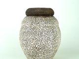 un vase blanc avec un couvercle marron posé sur une table