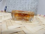 a small bottle of perfume sitting on a wicker table