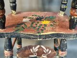 a small wooden chair with a painted seat on it