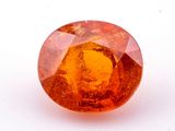 a close up of an orange sapphire stone on a white surface