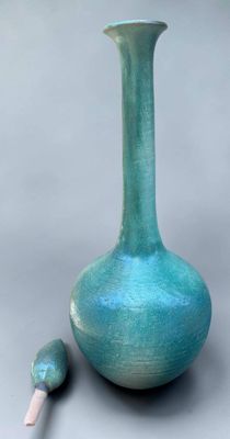 un vase bleu avec une poignée en bois à côté
