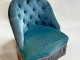 fauteuil en velours bleu avec des franges et des boutons sur le dossier