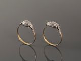 pair of gold and diamond rings on a reflective surface