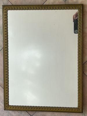 un miroir à cadre doré posé sur un sol carrelé