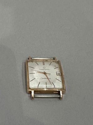 une petite montre carrée en argent posée sur une table