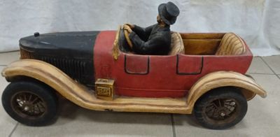 une statue représentant un homme assis dans une voiture rouge