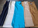 Plusieurs paires de pantalons sont disposées sur une table dans une pièce.
