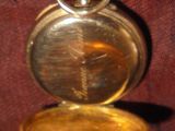 une vieille montre de poche posée sur un tissu rouge