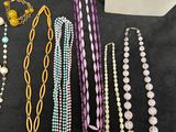 a table topped with lots of different colored necklaces and bracelets