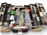 une valise remplie d'objets, posée sur une surface blanche