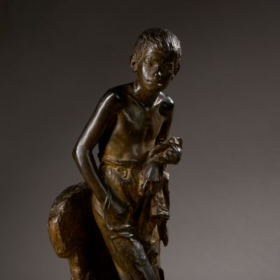 bronze statue of a boy with a dog on a rock