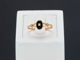 a close up of a gold ring with a black stone
