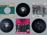 four beatles records on a white surface with a pink background