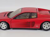 red model of a car on a white surface with a white background