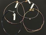 three different bracelets with tags on them on a black background