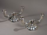 paire de bougeoirs plaqués argent sur un socle, sur fond gris