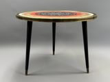 une table ronde dont le plateau présente un motif circulaire et dont les pieds sont noirs