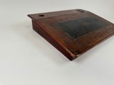 an old wooden box with a black leather cover on a white surface