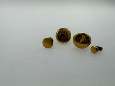two pairs of gold colored studs on a white surface