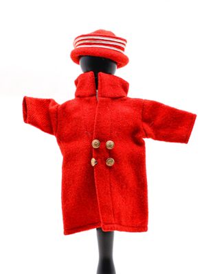 une poupée qui porte un manteau rouge et un bonnet rouge